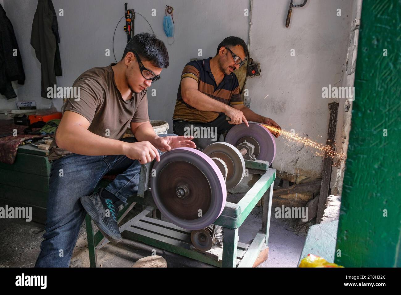 Osh, Kyrgyzstan - October 6, 2023: Men sharpening knives at the Jayma Bazaar in Osh, Kyrgyzstan. Stock Photo