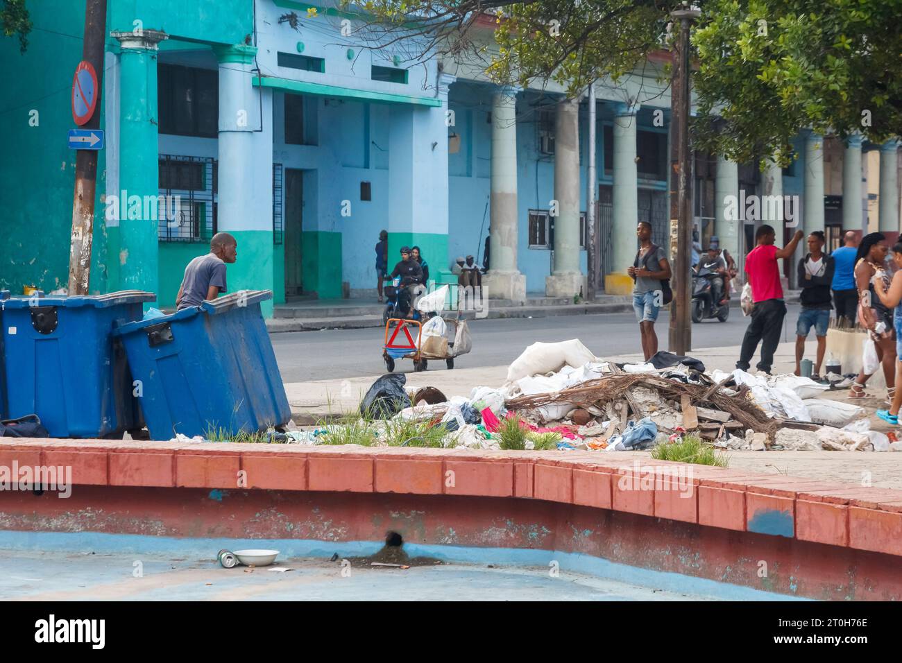 Havana, Cuba - September 29, 2023: Cuban people are out and about a small square with a garbage dump and a dry fountain. Stock Photo
