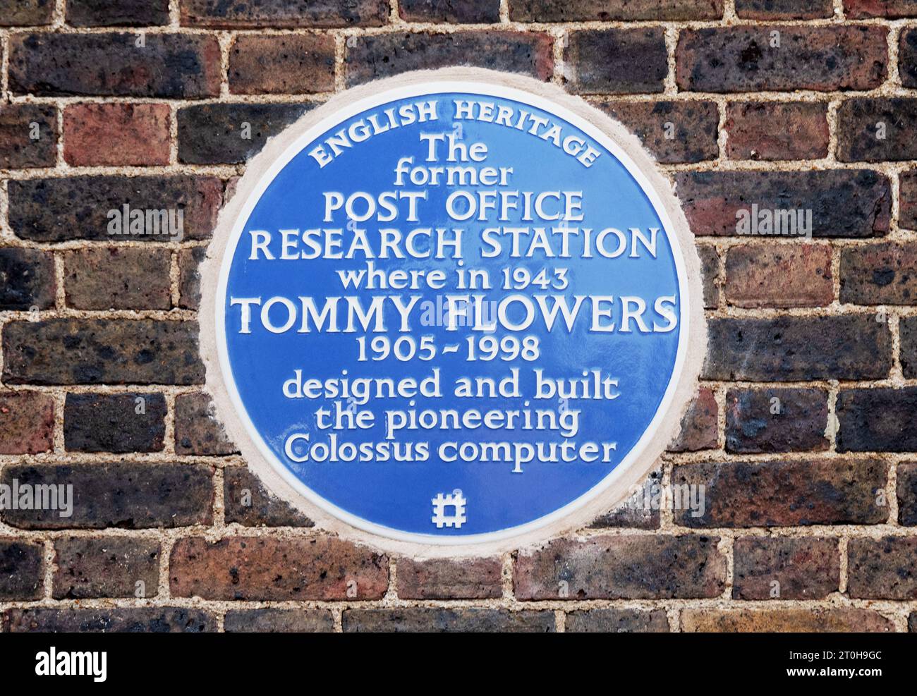 Tommy Flowers Blue Plaque for his WWII work in designing and building the worlds first electronic thermionic valve programable computer, Colossus, at the Post Offices Research Laboratories in Dollis Hill London. This was demonstrated in 1943 then later transferred to Bletchley Park where it assisted the war effort. When the Post Office Research Laboratories closed they were converted to flats, Chartwell Court. On September 6th 2023 during an English Heritage ceremony, the blue plaque was unveiled on the flats end wall, viewable from the adjacent Flowers Close. Credit: Stephen Bell/Alamy Stock Photo