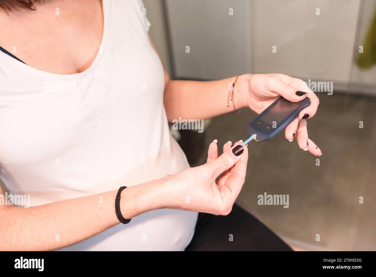 Young pregnant woman performing a gestational diabetes selftest to control sugar. Measuring the
