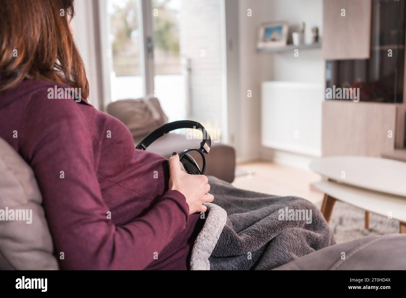 Detail of a young pregnant Caucasian woman connecting with the child putting music with headphones, in the well-being of her home Stock Photo