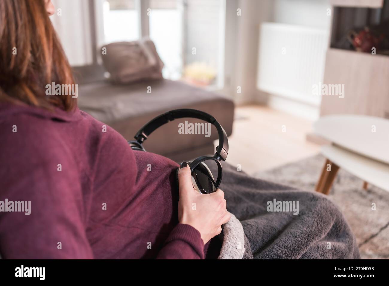 Detail of a young pregnant woman connecting with the child putting music with headphones, in the well-being of her home Stock Photo