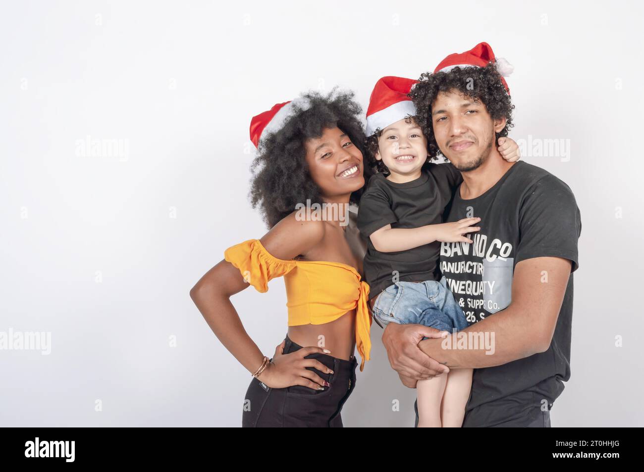multiracial family posing with a child in their arms wearing Christmas hats, portrait Stock Photo