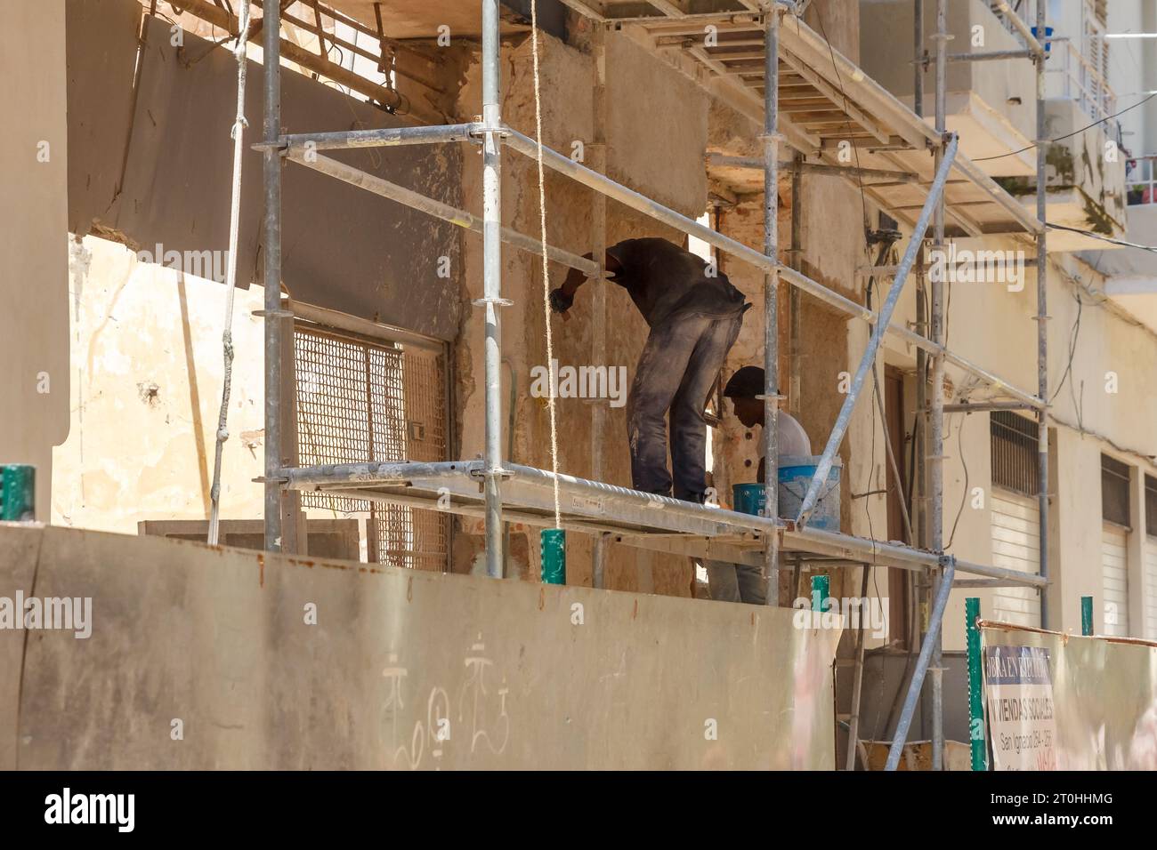 Two male construction workers are in a scaffolding. They are building  or repairing an apartment residential structure. Stock Photo
