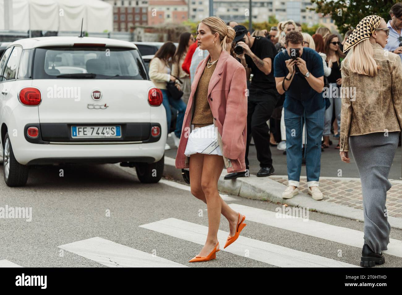 Emili Sindlev wears necklaces, a knit pullover, a pink suede oversized jacket, Prada bag, seen outside PRADA show during Milan Fashion Week Womenswear Stock Photo
