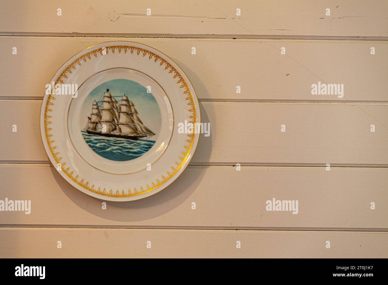 Decorative plate hanging on a painted wooden interior wall in Steveston British Columbia Canada Stock Photo
