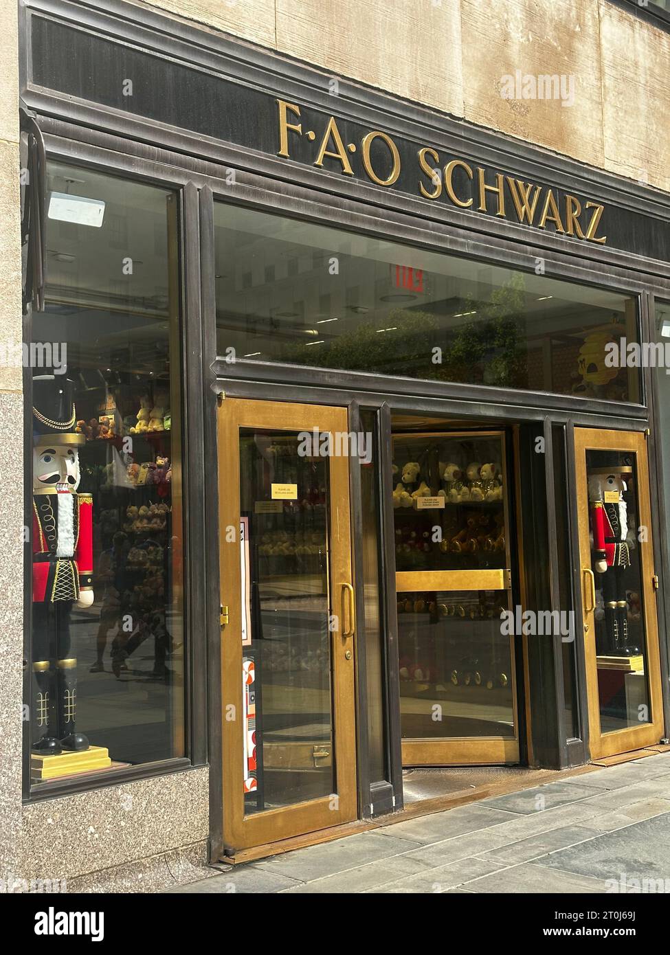 FAO Schwarz flagship entrance, Rockefeller Center NYC: gold lettering sign, large nutcracker soldiers flanking glass doors,Midtown Manhattan toy store Stock Photo