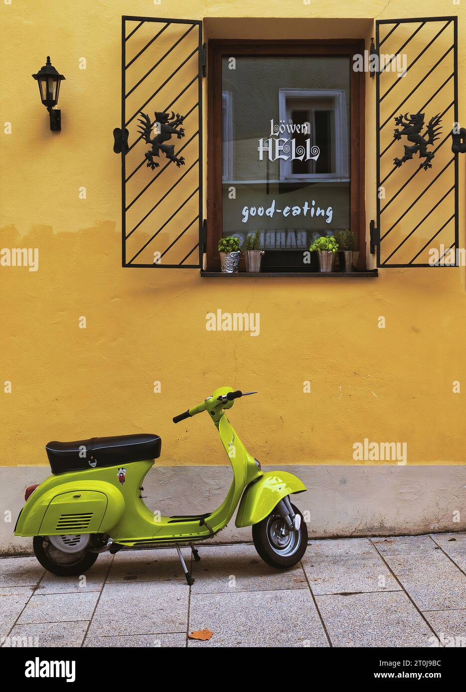 A little flavour of European cool with a vibrantly coloured scooter contrasting with the brightly painted cafe wall behind it. Stock Photo