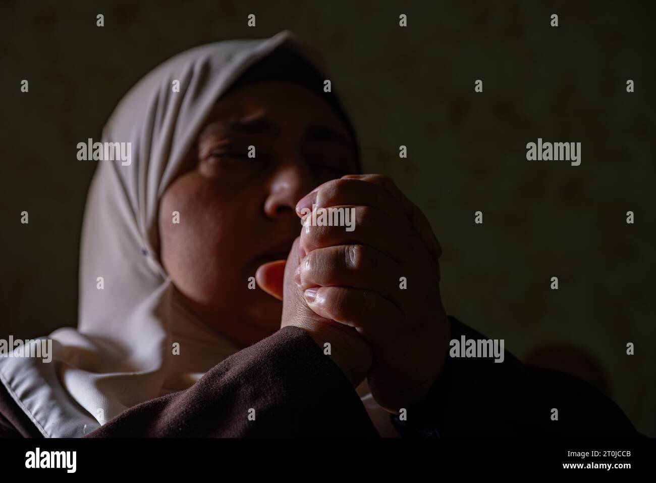 A Muslim woman raises her prayers to God to remove the affliction and illness from her and to relieve her of the calamities that have befallen her Stock Photo