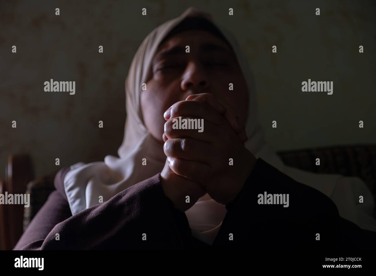 A Muslim woman raises her prayers to God to remove the affliction and illness from her and to relieve her of the calamities that have befallen her Stock Photo