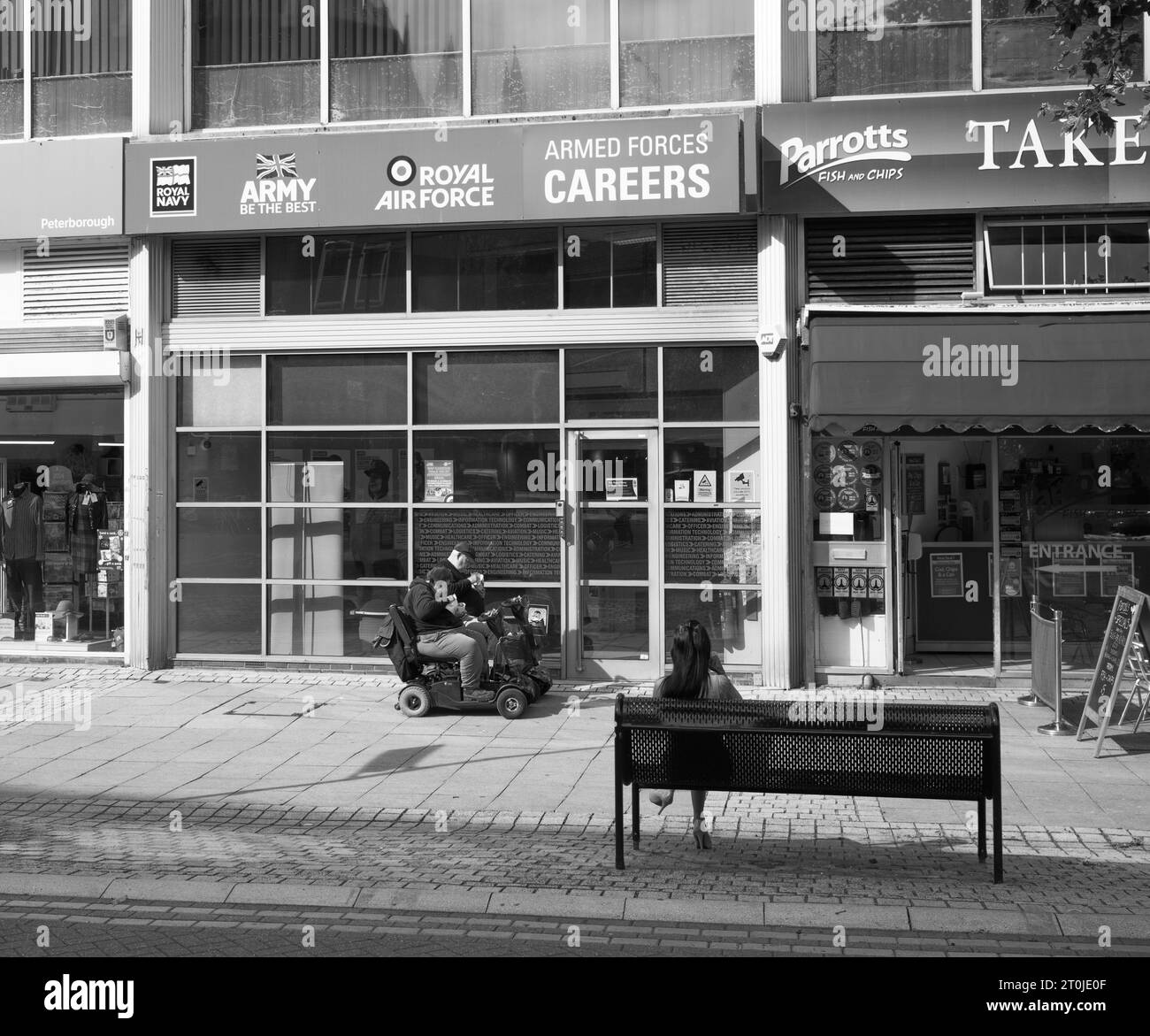 An older couple on mobility scooters eating outside a forces recruitment office in Peterborough Stock Photo