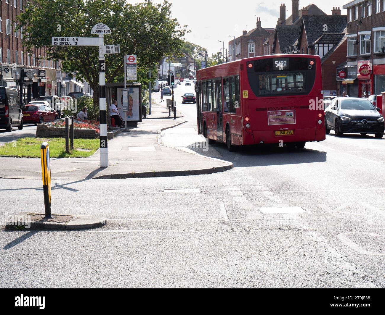 Loughton sign post with directions to  Abridge, Chigwell, Epping and Harlow, with single decker red bus, Loughton, Essex Stock Photo