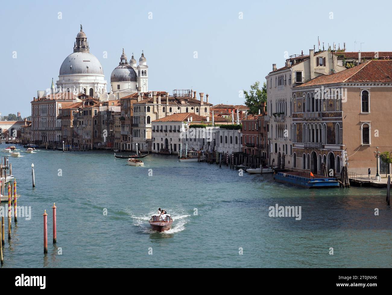 Scenes of Venice, Italy on October 7, 2023. A water taxi makes its way along the Grand Canal with the The Basilica of Santa Maria della Salute in the Stock Photo