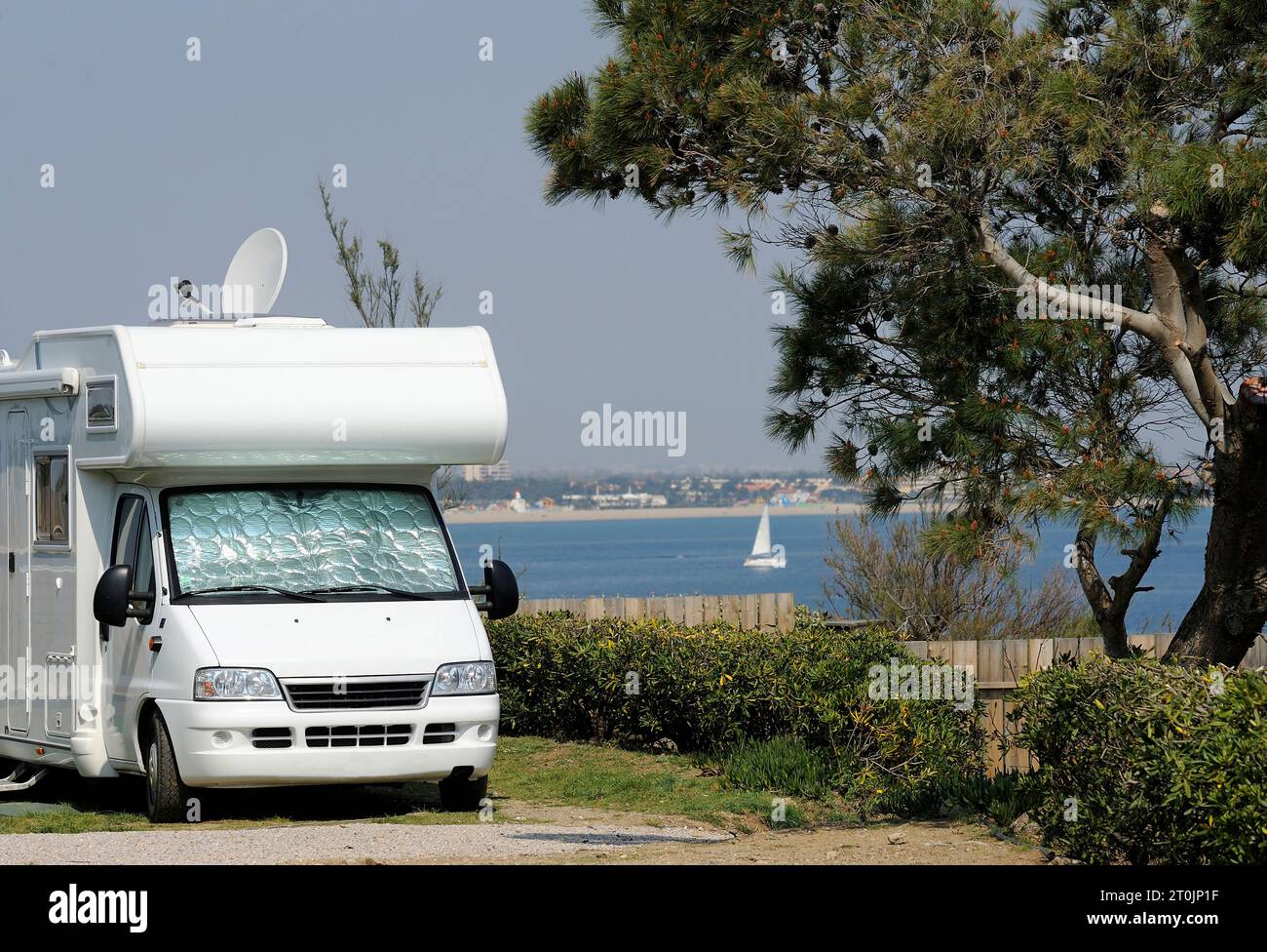Camper at a camping with view at the sea and in the distance is a sailing boat Stock Photo