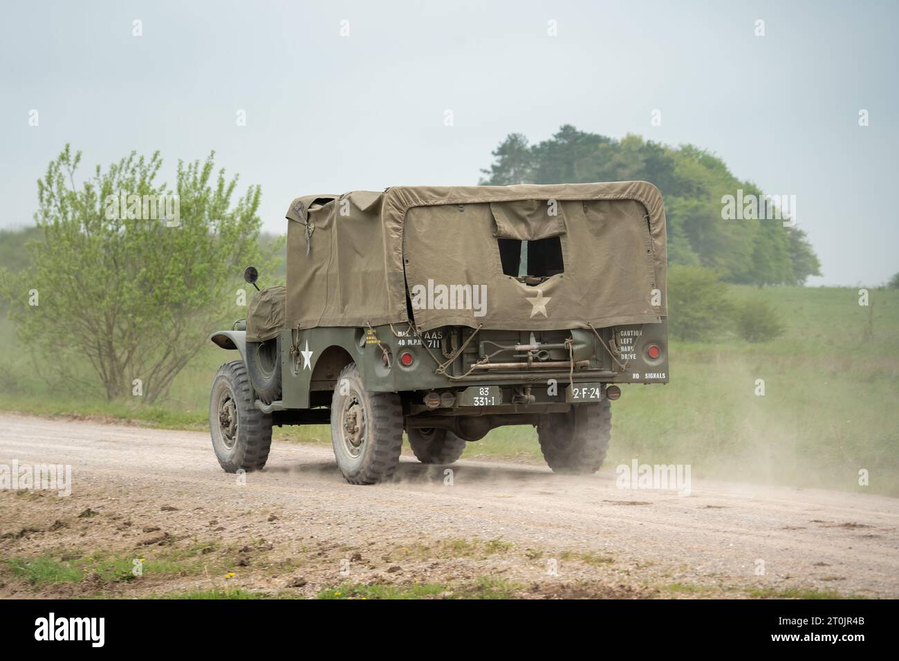an old military USA Jeep transport with canvass back cover, driving along a dirt track Stock Photo