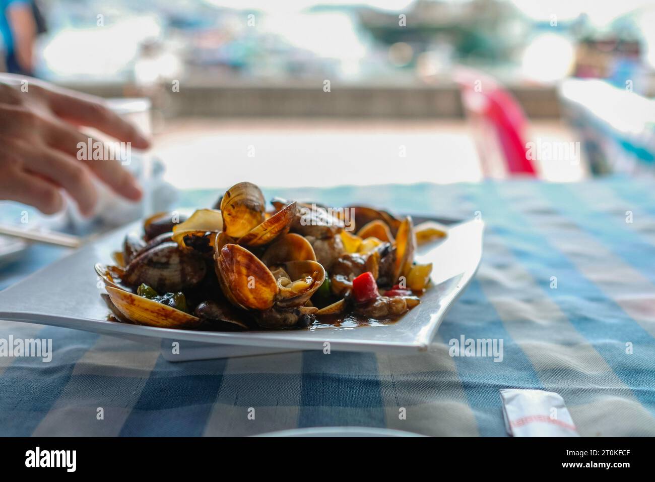 A plate of clams cooked in black bean chili garlic sauce at a Cantonese seafood restaurant along Cheung Chau Pier in Hong Kong Stock Photo