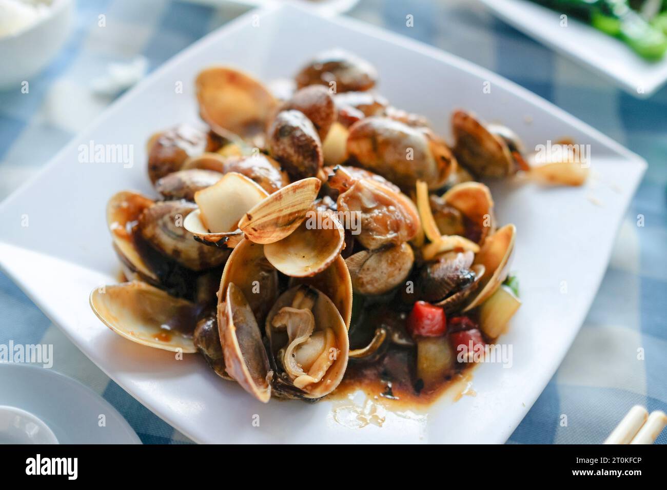 A plate of clams cooked in black bean chili garlic sauce at a Cantonese seafood restaurant along Cheung Chau Pier in Hong Kong Stock Photo