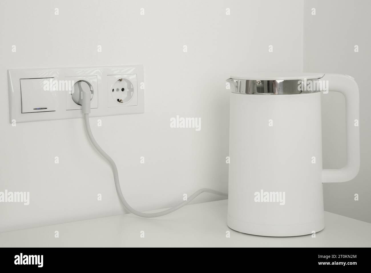 https://c8.alamy.com/comp/2T0KN2M/electric-kettle-plugged-into-power-socket-on-white-wall-2T0KN2M.jpg