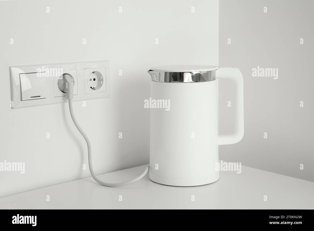 https://c8.alamy.com/comp/2T0KN2W/electric-kettle-plugged-into-power-socket-on-white-wall-2T0KN2W.jpg