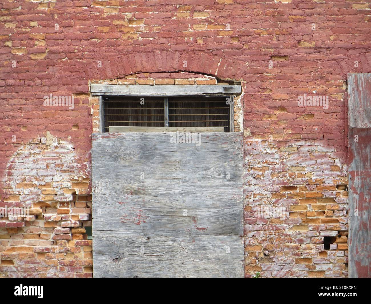 Boarded-up window on a red brick wall Stock Photo