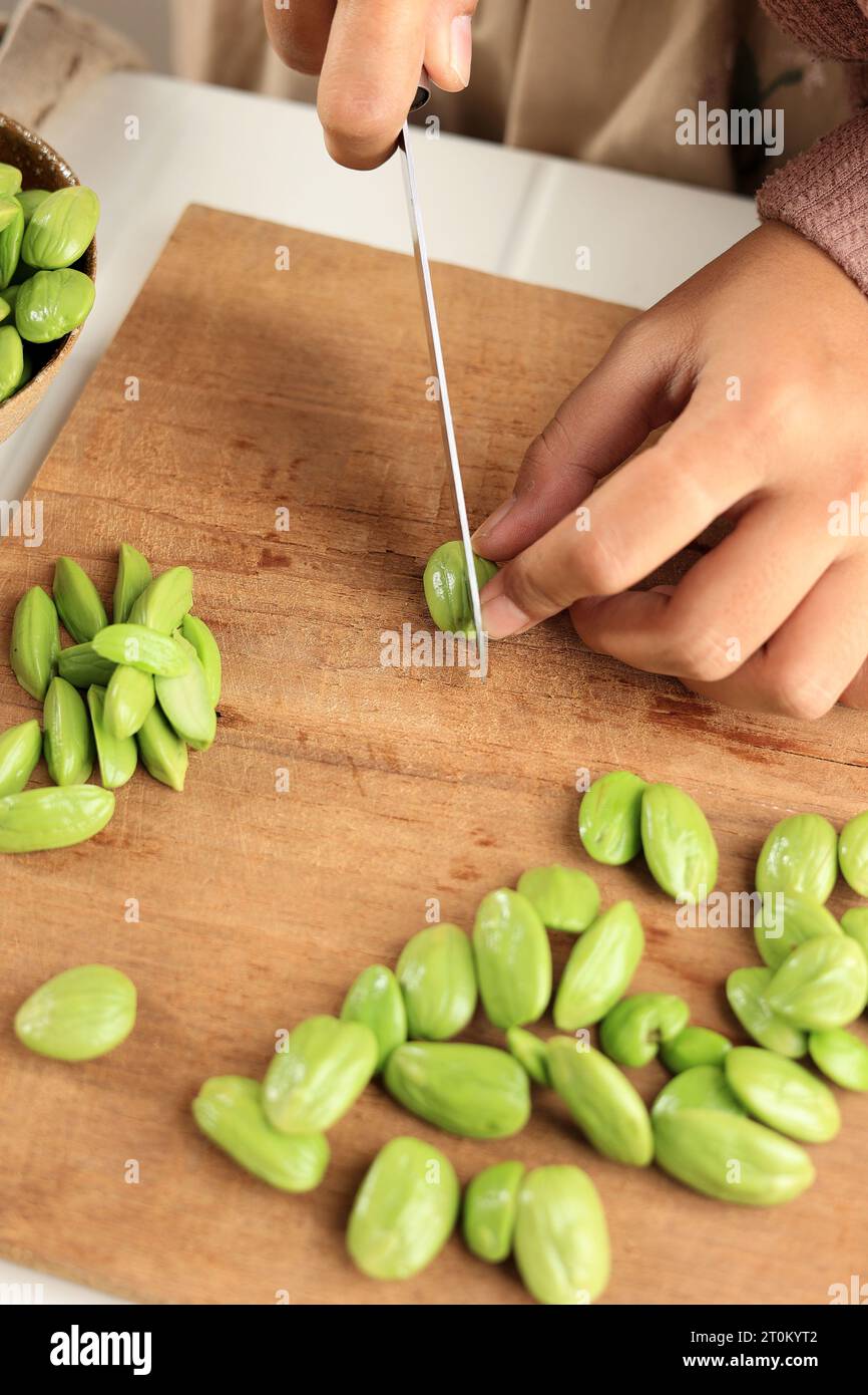 Female Chef Slicing Cut Pete or Parkia Speciosa on Wooden Stock Photo