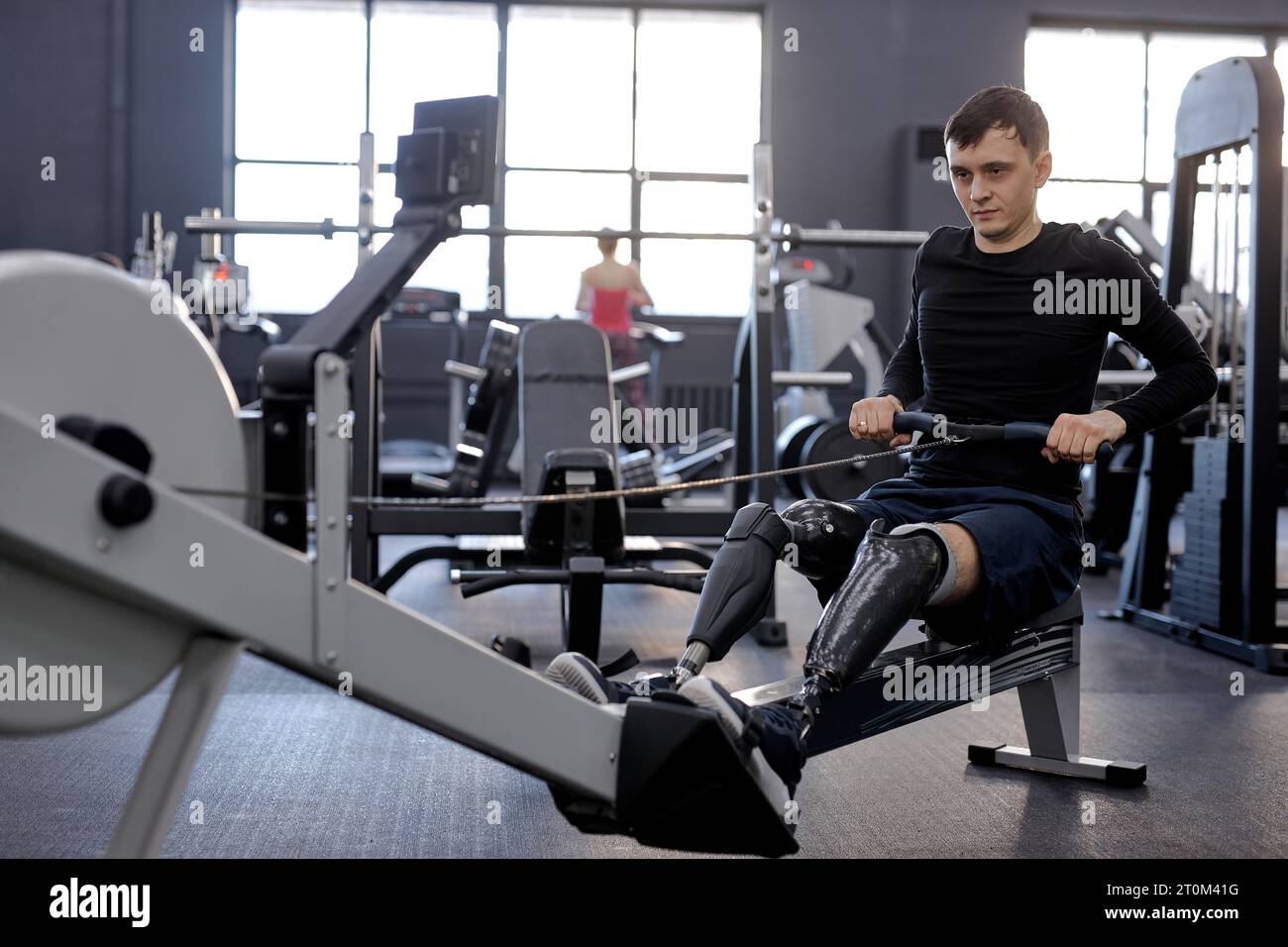 strong man concentrated on pilling rowing machine, side view shot. total-body fitness Stock Photo