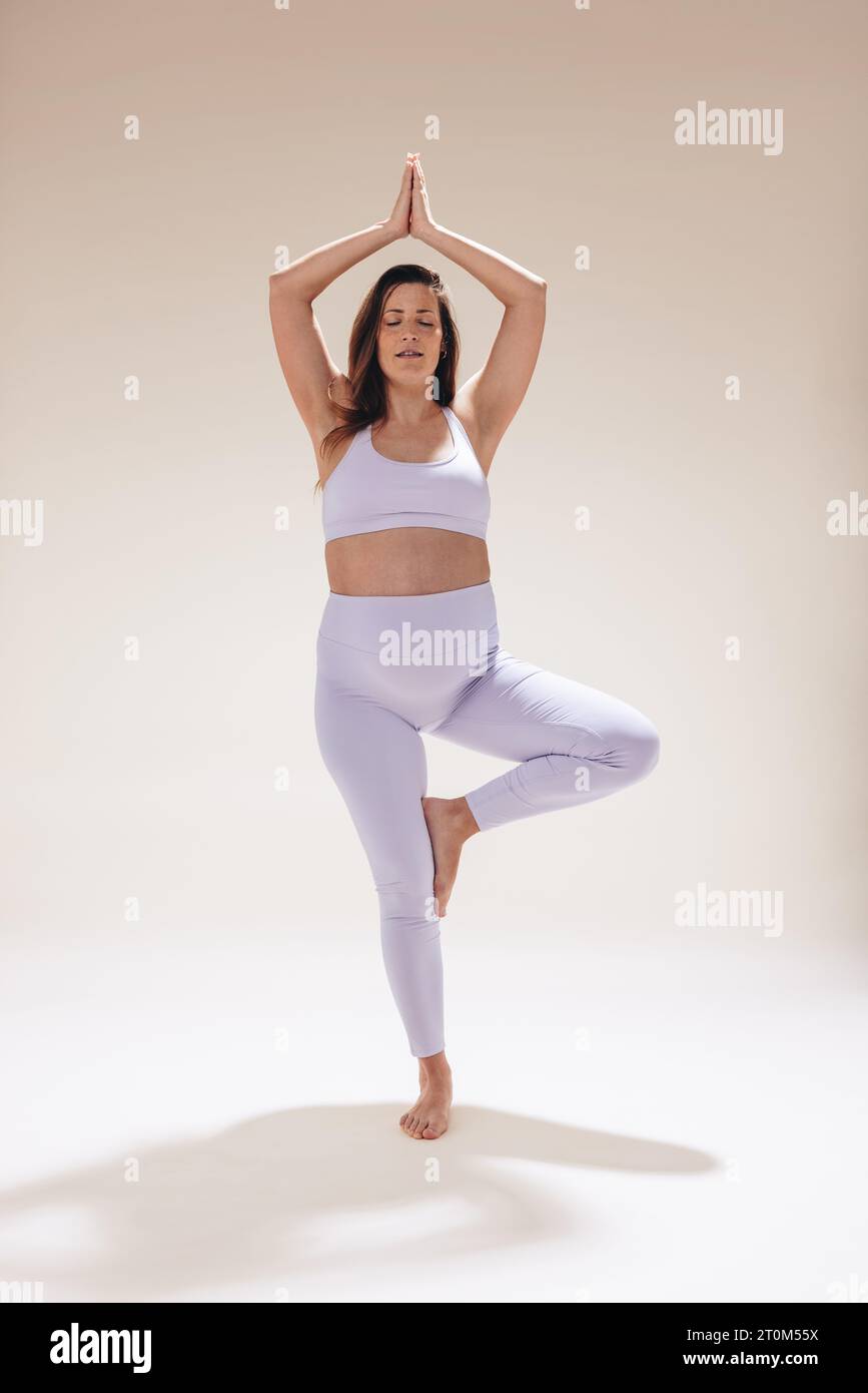 Caucasian pregnant woman practicing prenatal yoga in a studio. With her baby bump, she focuses on balance and meditation embracing a healthy lifestyle Stock Photo