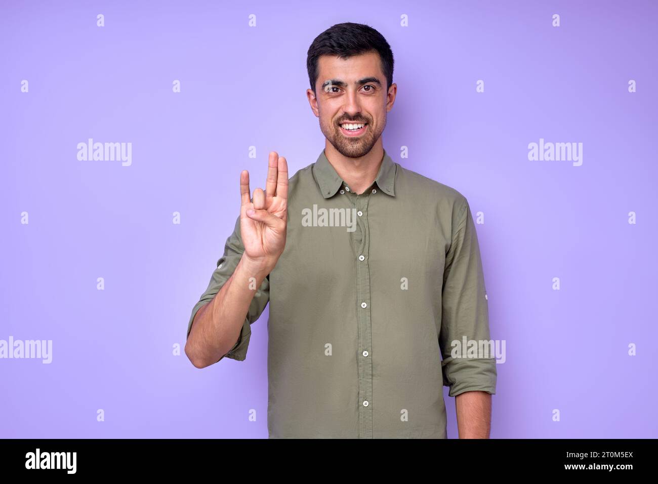 happy handsome smiling deaf mute man using sign language on blue background Stock Photo