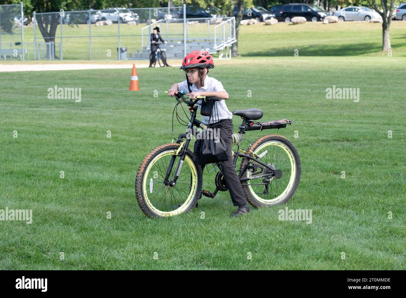 A young Hasidic boy with long peyot pauses on his bike during Sukkos