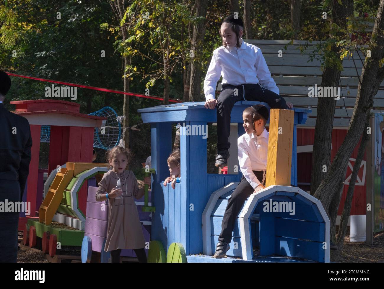 On Sukkos, a group of orthodox Jewish children climb on a wooden train