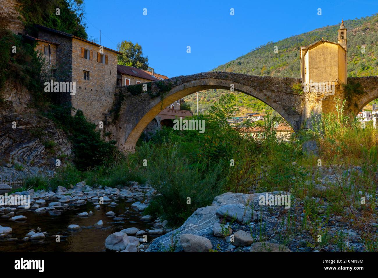 Medieval stone bridge over Argentina river and chapel in small town Badalucco. Badalucco is a comune in the Province of Imperia in Italy. Stock Photo
