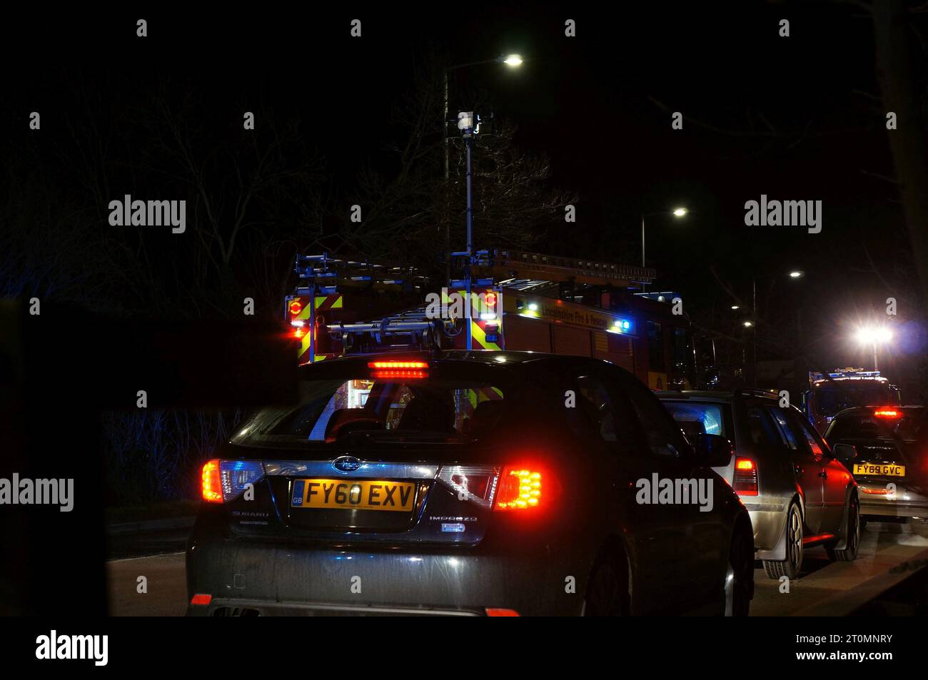 traffic passing an accident at night with flashing lights from emergency vehicles. Stock Photo