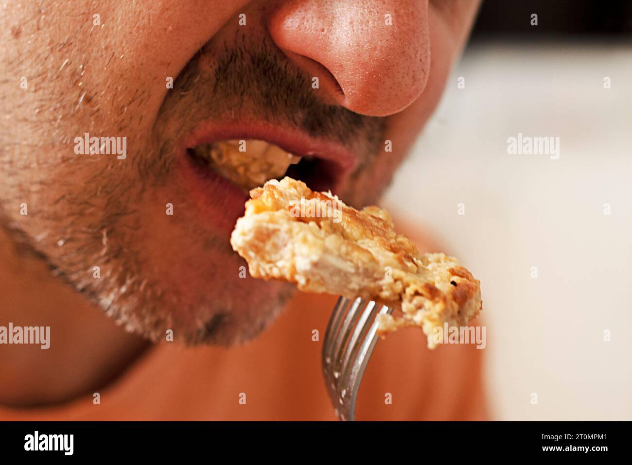 man taking a bite of a piece of fried chicken meat from a fork. dinner