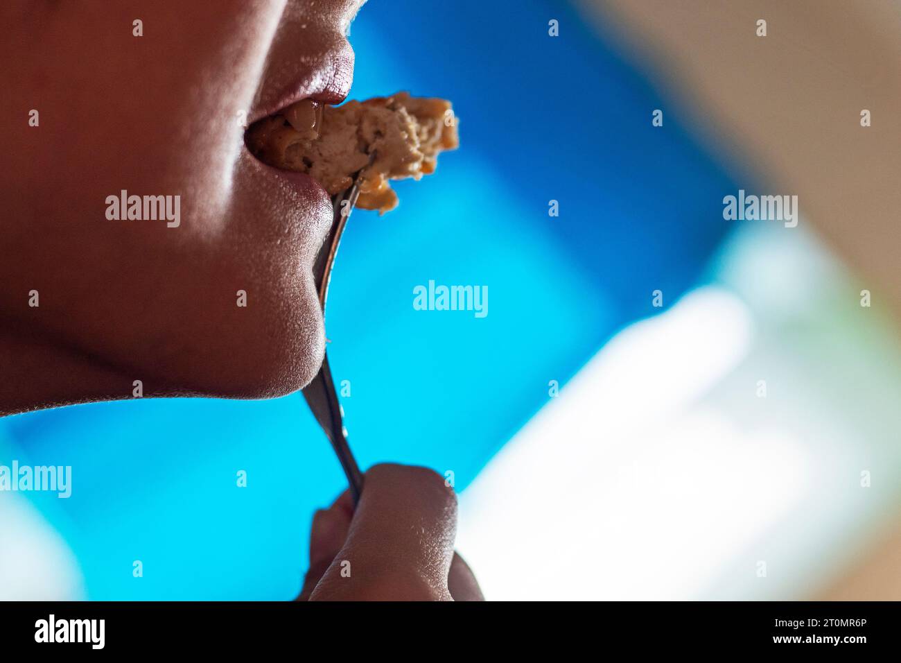 boy bites a piece of meat from a fork Stock Photo Alamy