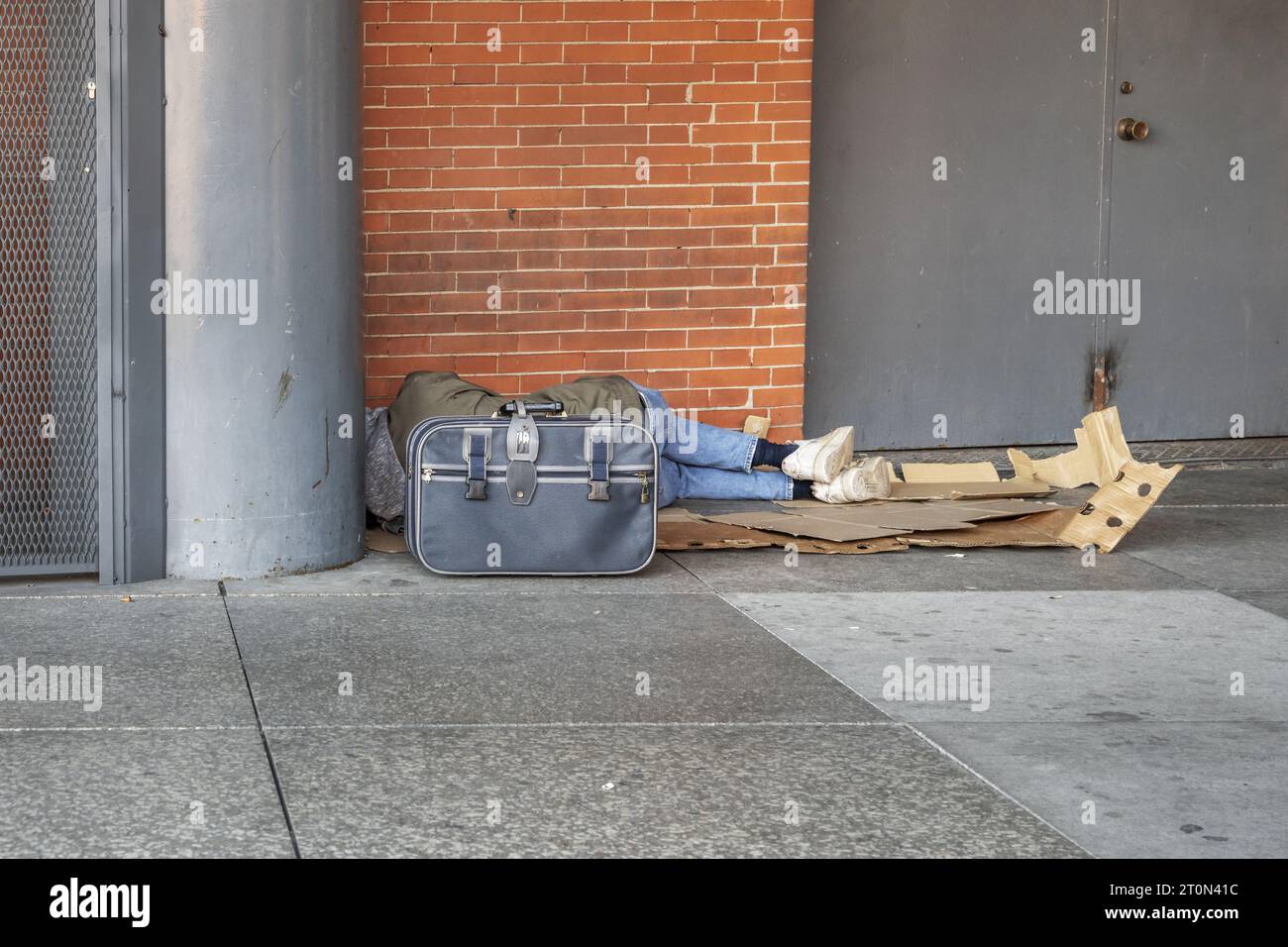 A homeless man sleeping on cardboard on a street corner Stock Photo - Alamy