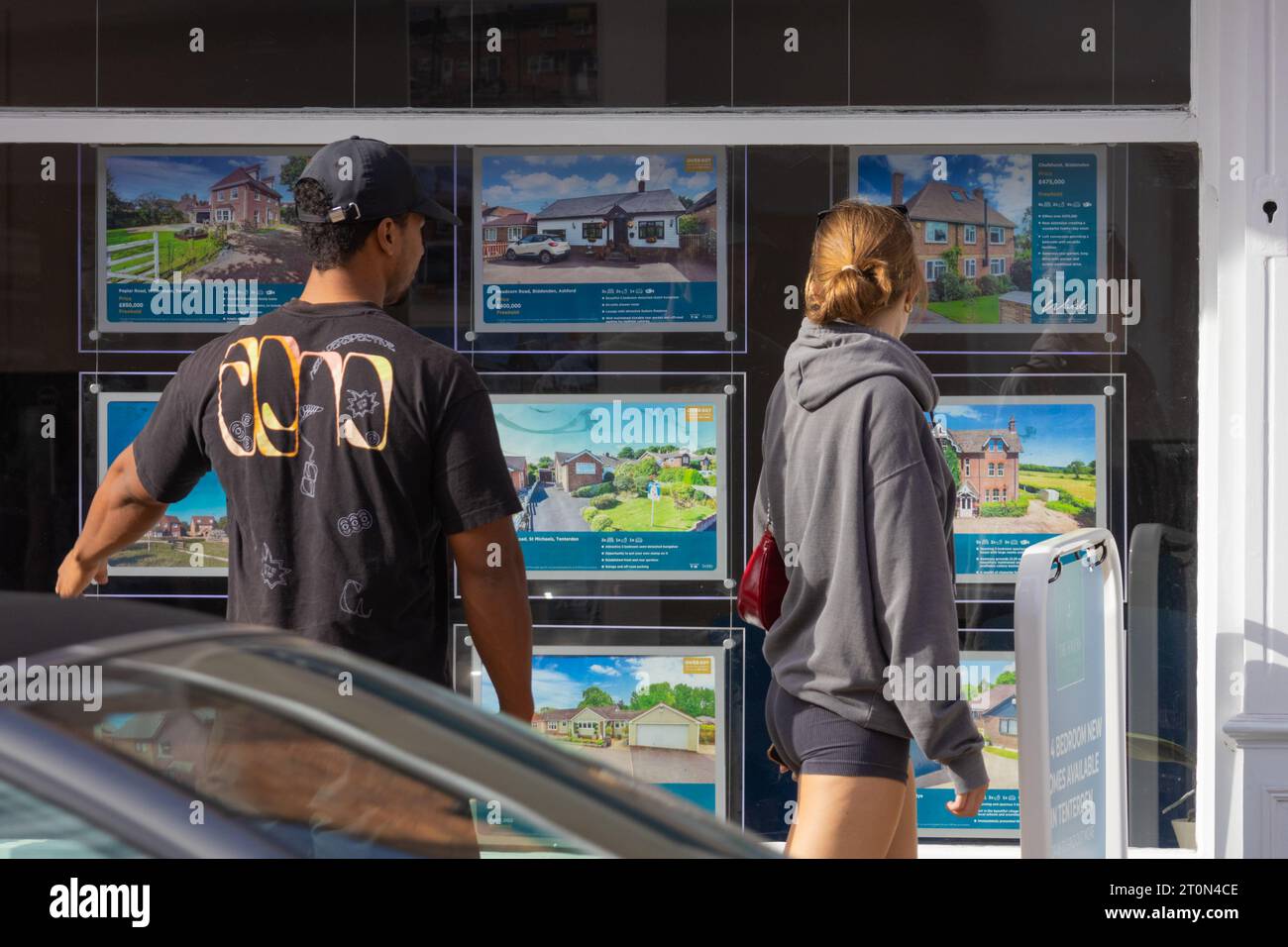 Young couple looking at property in estate agent window, tenterden, kent, uk Stock Photo