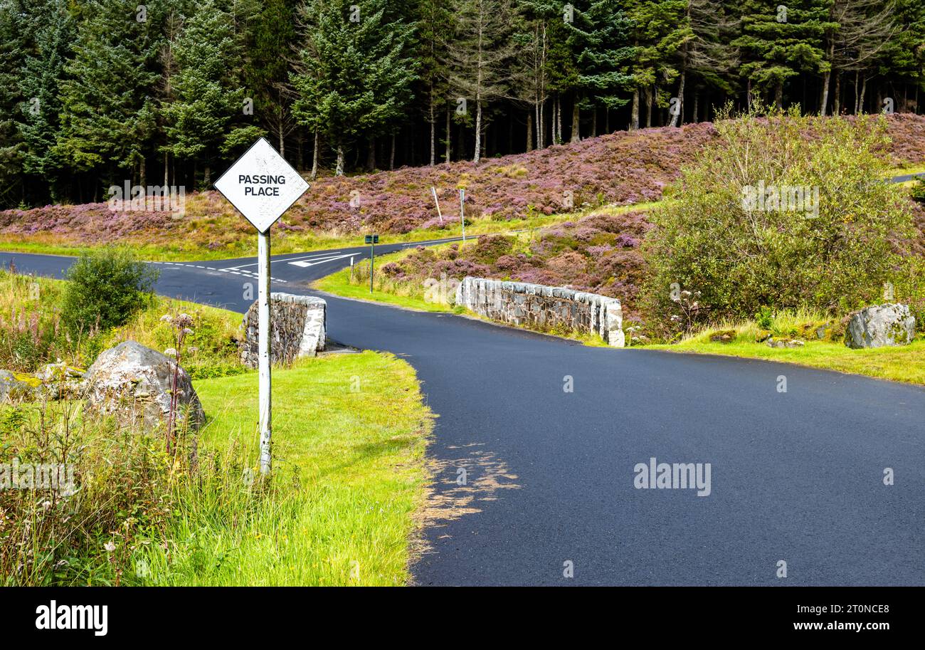 Galloway Forest Park, Black single  tarmac road with no road markings and passing place sign near old stone bridge Stock Photo