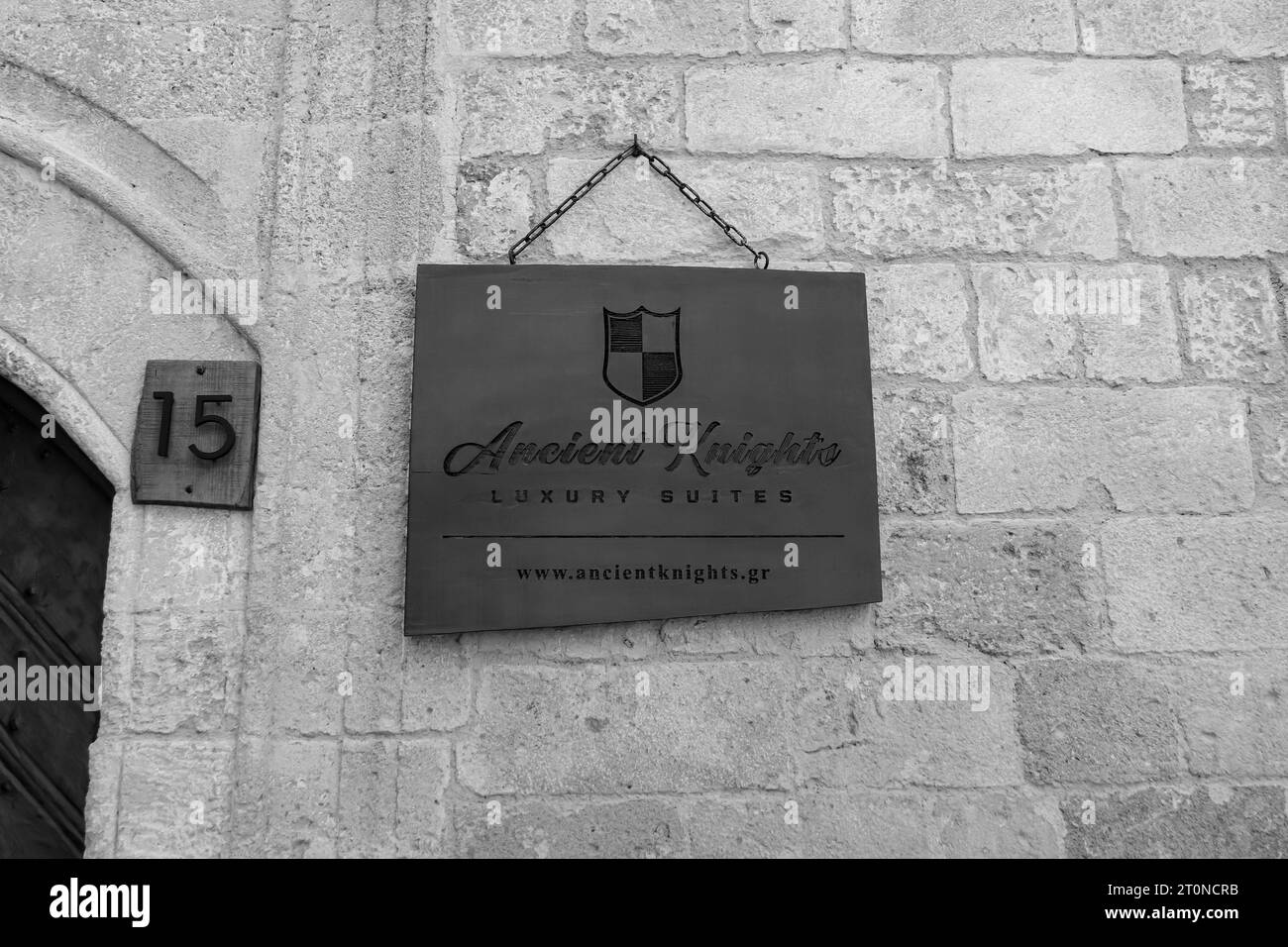 The Ancient Knights Luxury Suites accommodations wooden entrance hanging sign at the Rhodes, Old Town rental property in black and white Stock Photo