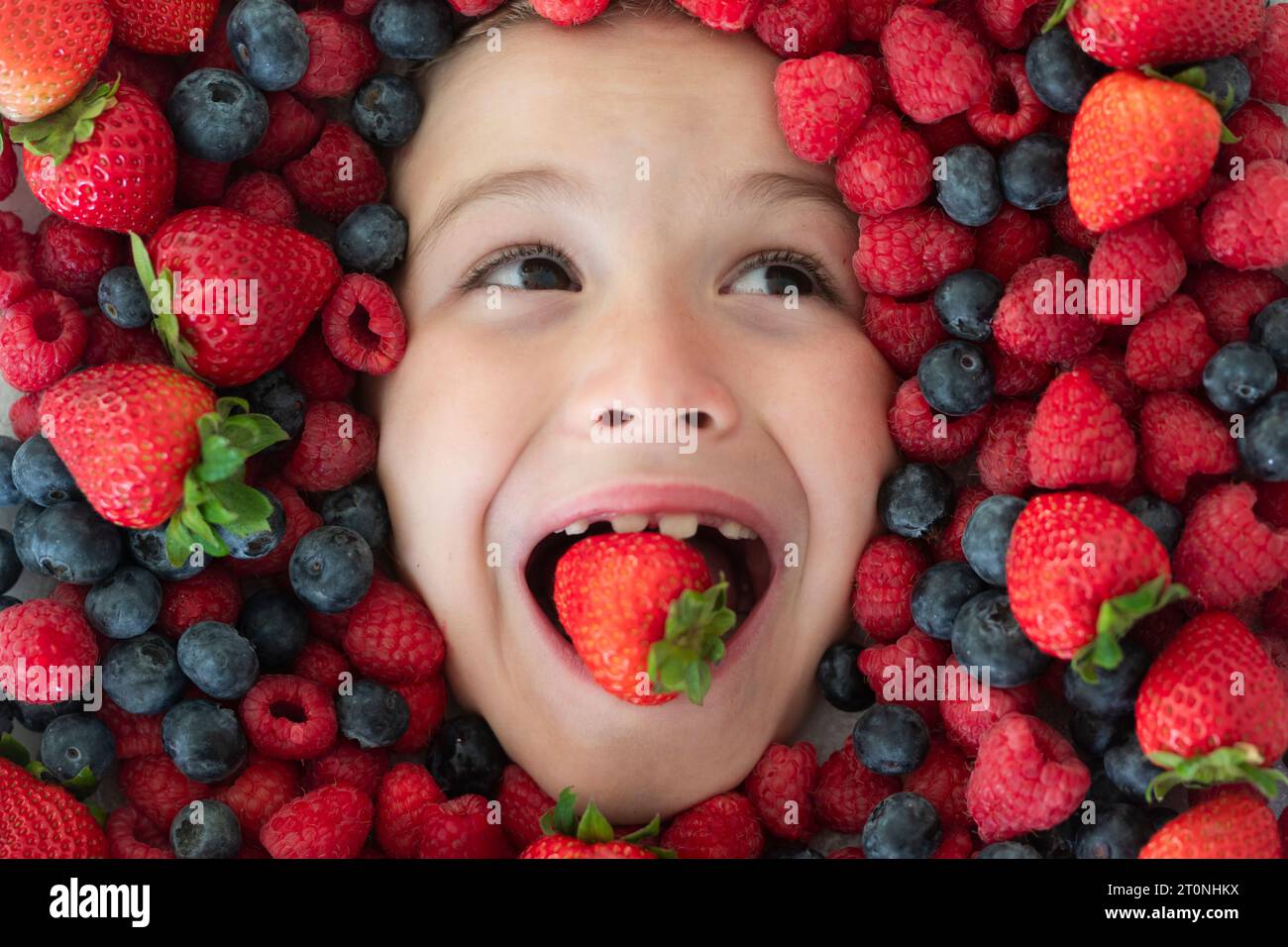 Mix of strawberry, blueberry, raspberry, blackberry background. Berries close up near kids face. Fresh berries, top view. Mix of raw fresh berries fru Stock Photo