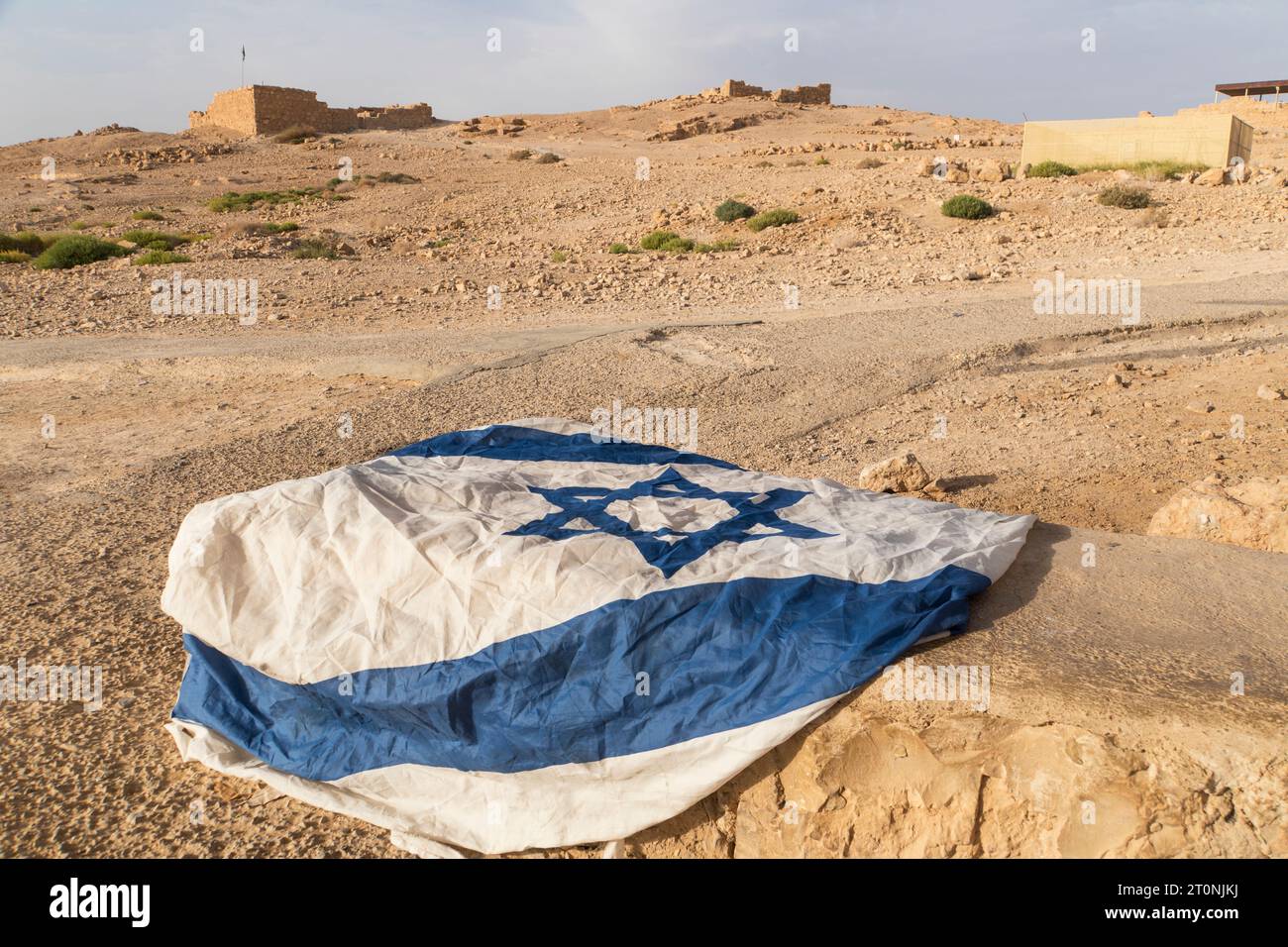 The rumpled Israeli flag left on the dry soil Israel. The national symbol of Israel Patriotic feeling. Nation Stock Photo