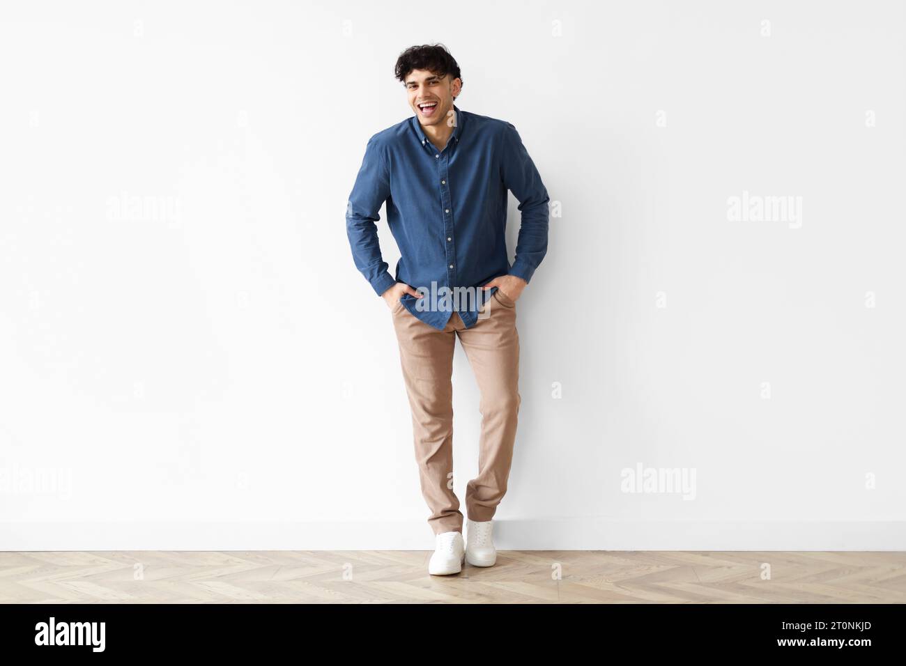 Smiling Middle Eastern Young Guy Standing, White Wall Background Stock Photo