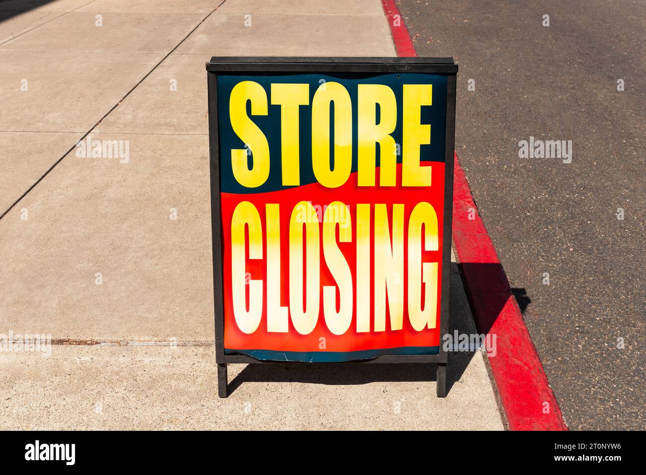 Store closing sign on the sidewalk in front of a retail store going out of business. Stock Photo