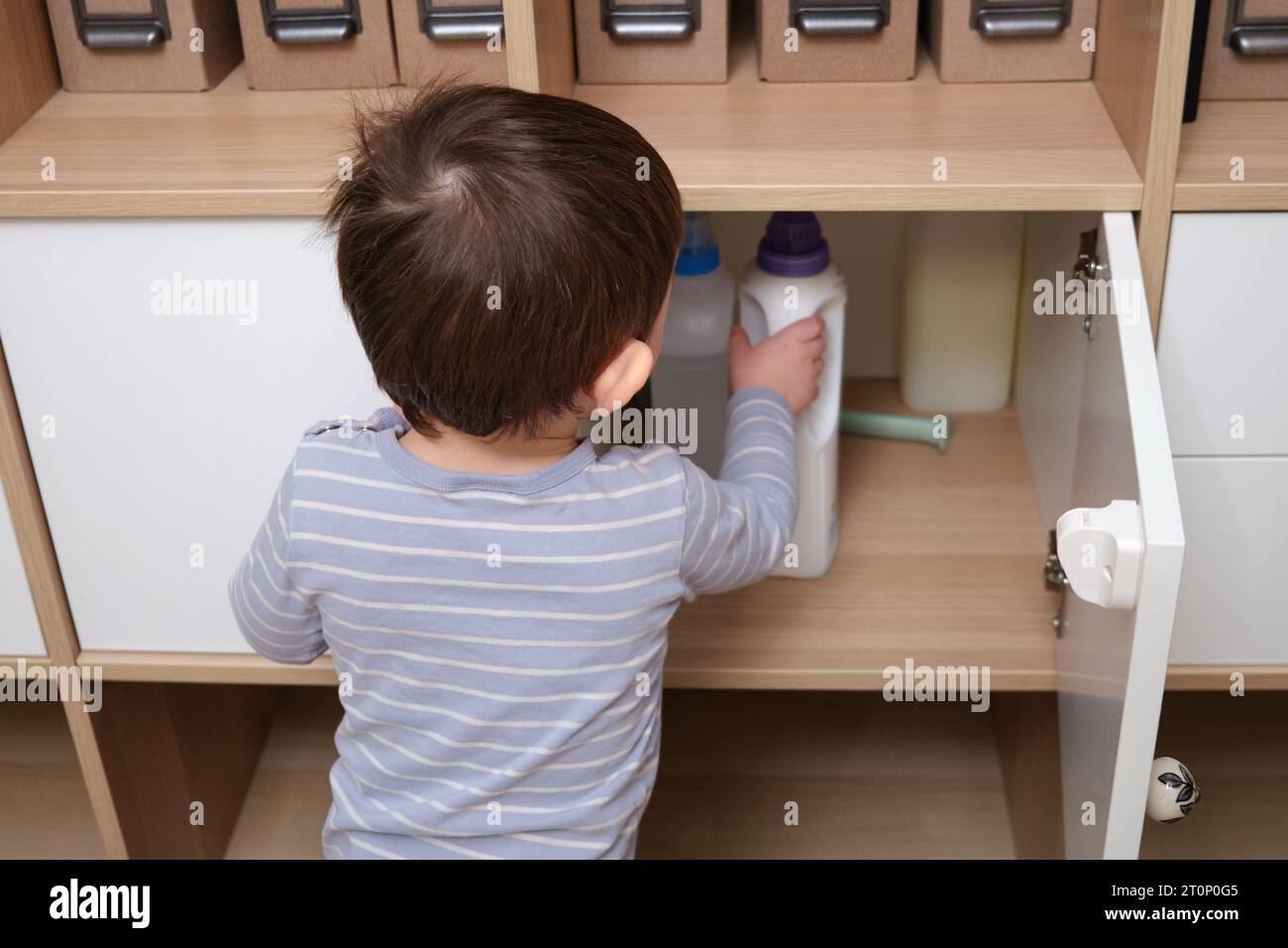 Toddler baby plays with household chemicals and detergent from the