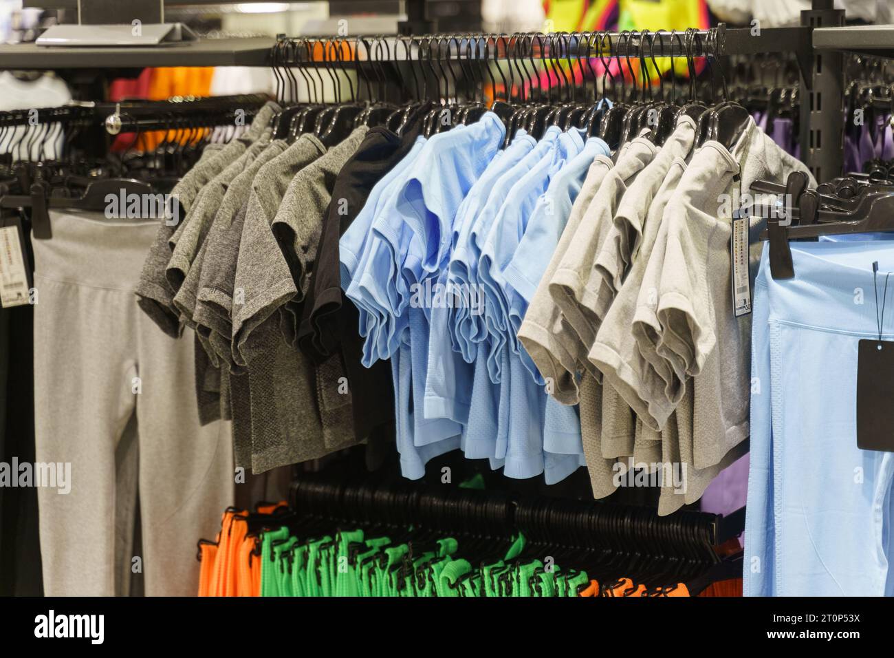 Women's T-shirts - short sleeve shirts hanging on hangers in a clothing store. Close-up, background. Selective sharpening. Stock Photo