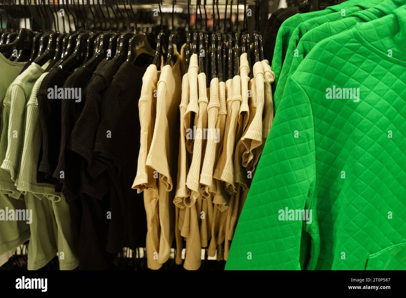 Women's short-sleeved jumpers hang on hangers in a clothing store. Close-up, background. Selective sharpening. Stock Photo