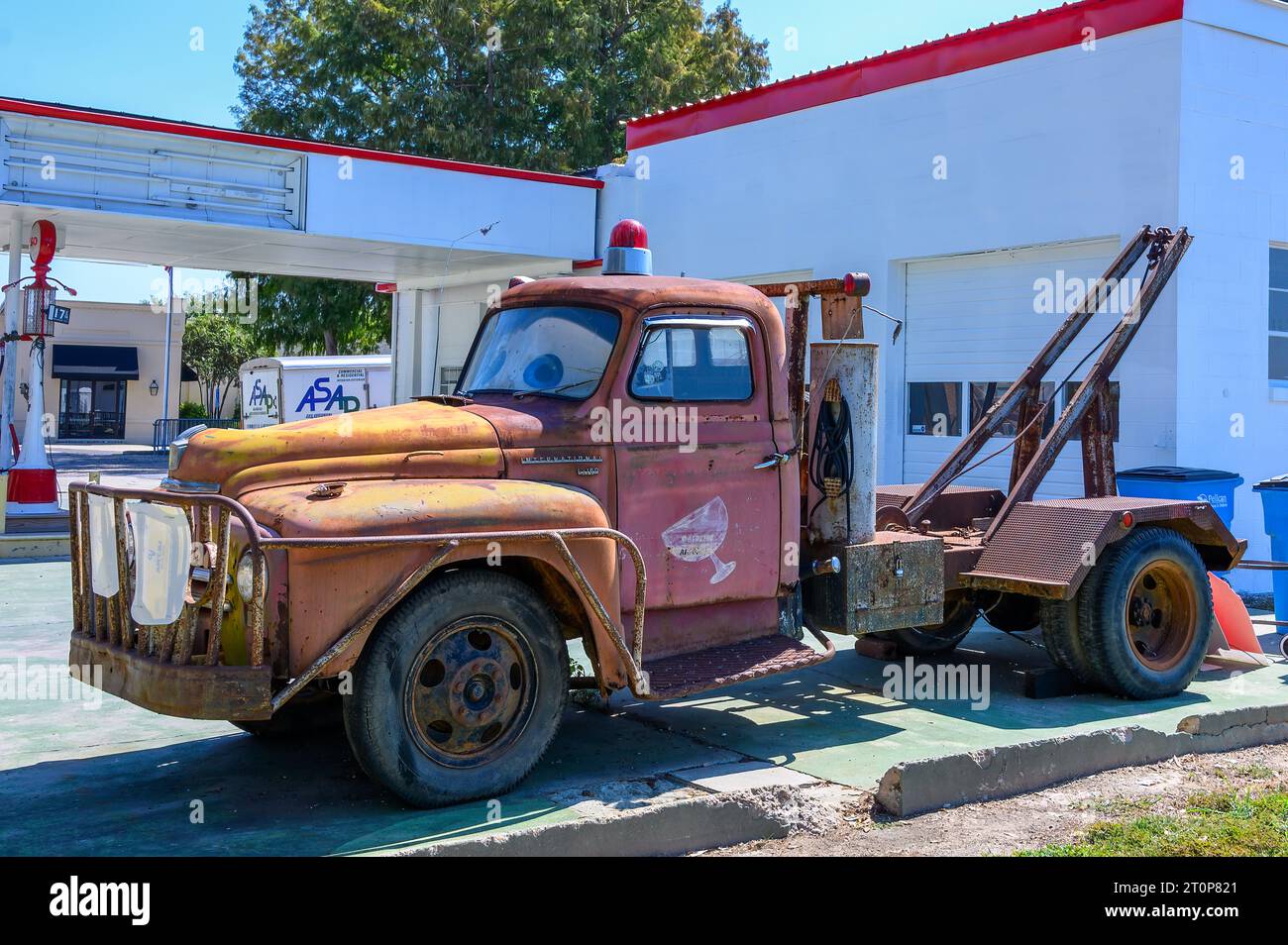 NEW ROADS, LA, USA - SEPTEMBER 19, 2023: Full view of a rusted 1950s International L-160 tow truck in front of a retro gas station Stock Photo