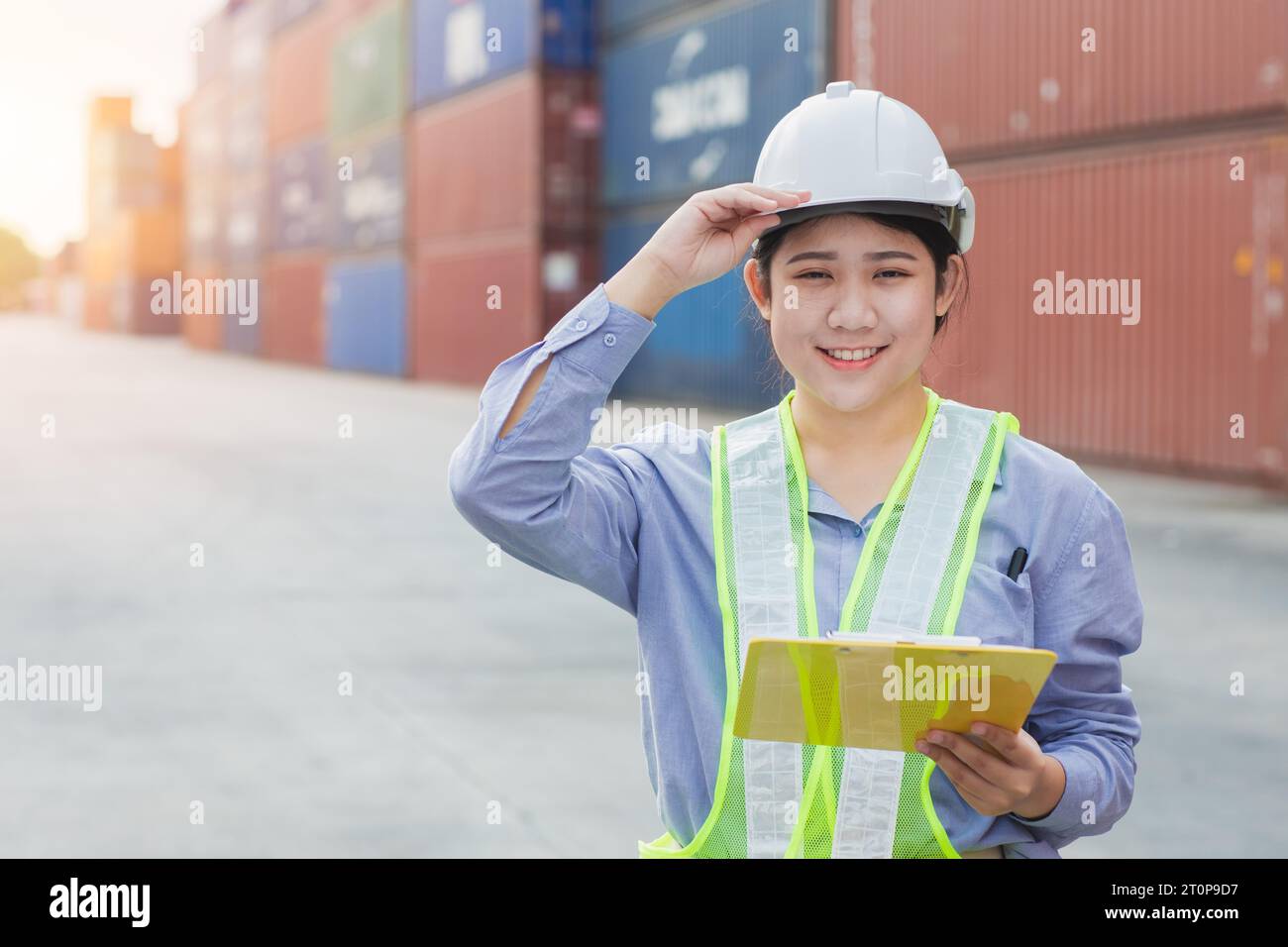 Asian woman happy dock worker control loading containers cargo at shipyard. Marine and carrier staff manager employee. cargo loading operator shipping Stock Photo