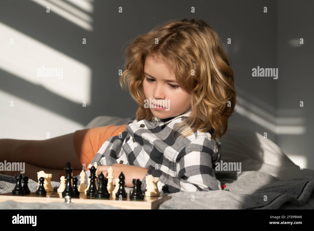 Kid play chess at home. Clever child thinking about chess. Kids early development Stock Photo