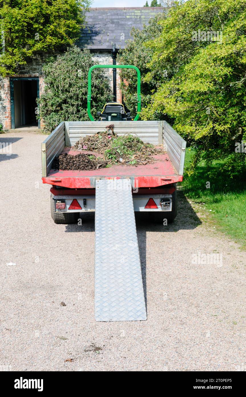 Tractor and trailer parked up with small amount of weeds/garden waste in trailer and ramp for loading and unloading Stock Photo