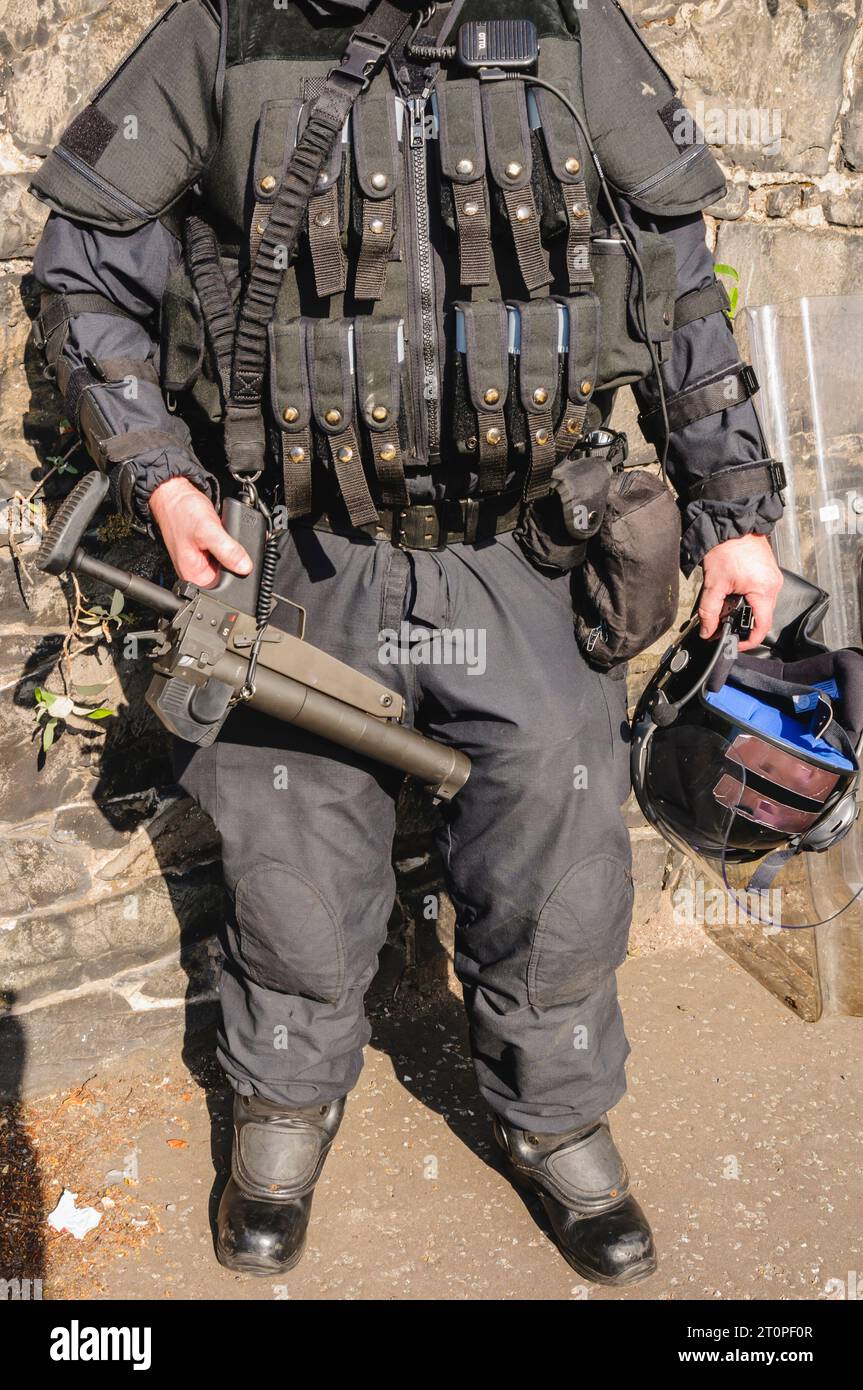 Police officer with vest loaded with AEPs, and carrying a Heckler and Koch L104A1 37mm single-shot AEP launcher Stock Photo